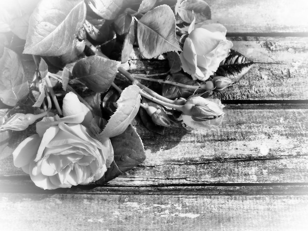 Foto rosen auf einem holztisch postkarte in grauem monochrom-filter glückwünsche oder ausdrücke des bedauerns textfreiraum rosen auf holzhintergrund schöner blumenstrauß für eine frau weiße vignettierung