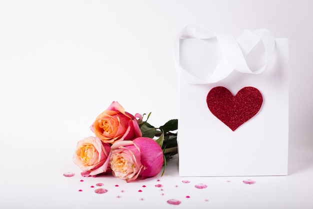 Rosen und Geschenk in Papierpackung mit rotem Herzen