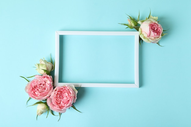 Rosen und leerer Rahmen auf blauem Hintergrund