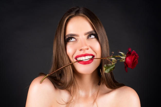 Rosenblüten in den roten Lippen einer Frau und Rosenschönheitsmädchen mit sexy Frau des sinnlichen Mundes mit Rot