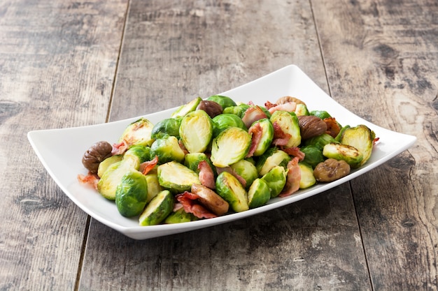 Rosenkohl mit Kastanien und Speck auf Holztisch