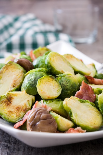 Rosenkohl mit Kastanien und Speck auf Holztisch