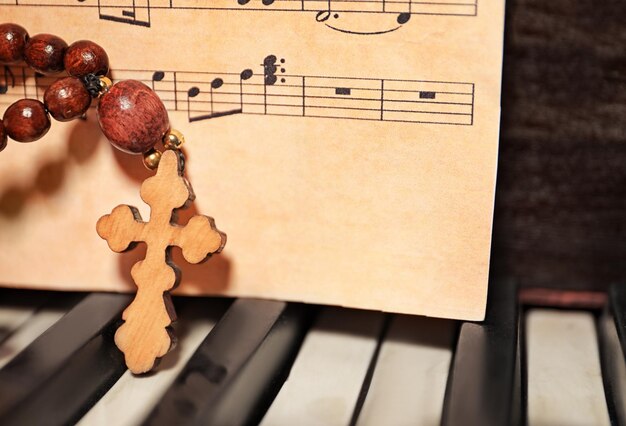 Rosenkranzperlen und Holzkreuz auf Klavier, Nahaufnahme