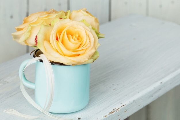 Rosenstrauß im Becher auf Tisch