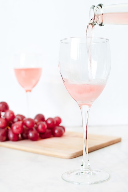 Roséwein wird aus einer Flasche in ein Glas gegossen.