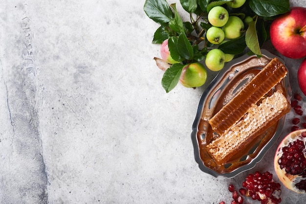 Rosh Hashaná Tarro de miel panal de manzana y granada en una mesa de fondo de hormigón rústico antiguo gris Tarjeta de felicitación de vacaciones de Año Nuevo judío Atributos de vacaciones de Rosh Hashaná Espacio para texto