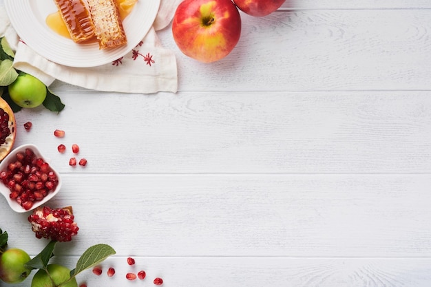 Rosh Hashaná Tarro de miel panal de manzana y granada en la mesa de fondo rústico antiguo de madera blanca Tarjeta de felicitación de vacaciones de Año Nuevo judío Atributos de vacaciones de Rosh Hashaná Espacio para texto