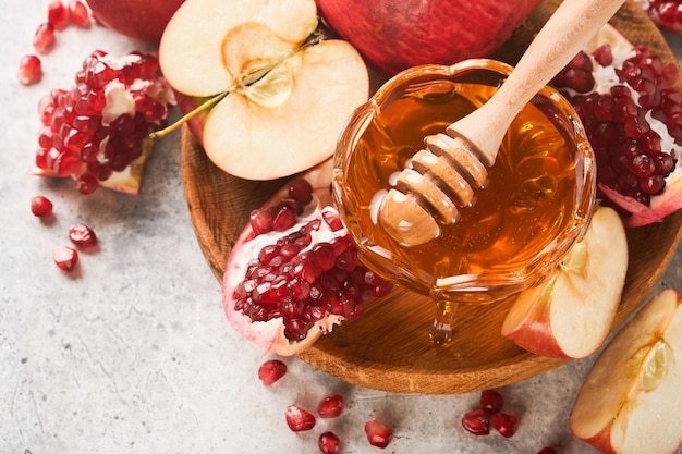 Rosh Hashanah Granatäpfel und Honig traditionelle Produkte zum Feiern auf rustikalem grauem Hintergrund Jüdischer Herbst Rosh Hashana Feier Jüdischer Feiertag Rosh Hashana Design Selektiver Fokus