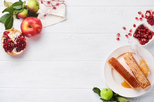 Rosh Hashanah Honey favo de mel maçã e romã na mesa de fundo rústico velho de madeira branca Cartão de saudação de feriado de ano novo judaico Atributos de feriado de Rosh Hashanah Espaço para texto