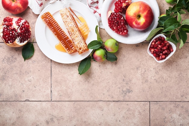 Rosh Hashanah Honigglas Wabenapfel und Granatapfel auf hellbeigem alten rustikalen Betonhintergrundtisch Jüdische Neujahrsgrußkarte Rosh Hashanah Feiertagsattribute Platz für Text