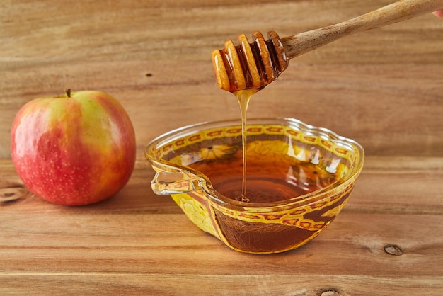 Rosh hashanah jüdisches Neujahrsfeiertagskonzept Schale in Form eines Apfels mit Honig und Äpfeln traditionelle Symbole des Urlaubs auf Holzhintergrund