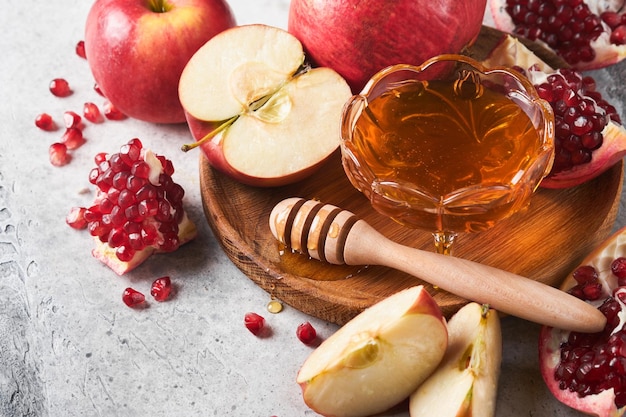 Rosh hashanah maçãs de romã e mel produtos tradicionais para celebração em fundo cinza rústico outono judaico celebração de rosh hashana feriado judaico projeto de rosh hashana foco seletivo