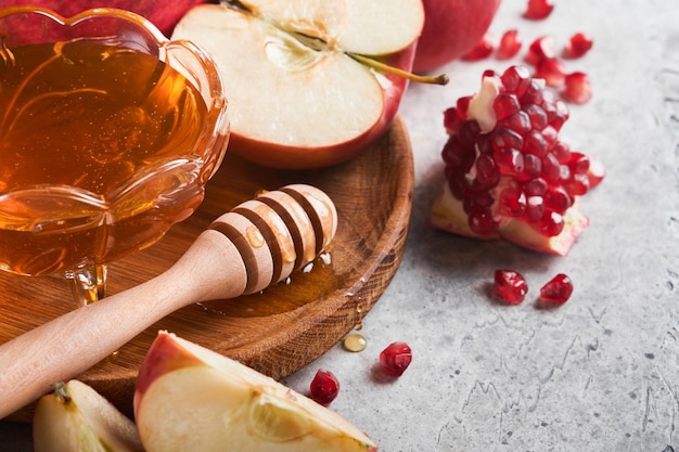 Rosh Hashanah Maçãs de romã e mel produtos tradicionais para celebração em fundo cinza rústico Outono Judaico Celebração de Rosh Hashana Feriado judaico Projeto de Rosh Hashana Foco seletivo