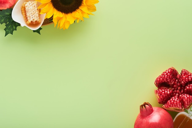 Rosh Hashanah Miel de manzana de granada madura y flores amarillas de girasol en composición de fondo verde con símbolos atributos de vacaciones judías de Rosh Hashanah Vista superior con espacio de copia