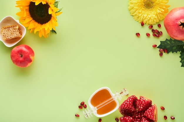 Rosh hashanah romã madura maçã mel e girassol flores amarelas na composição de fundo verde com símbolos judaicos rosh hashanah feriado atributos vista superior com espaço de cópia