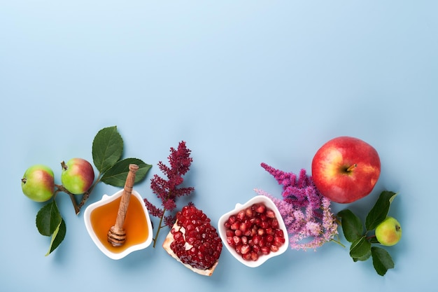 Rosh Hashanah Tarro de miel panal de manzana y granada sobre fondo azul simple Tarjeta de felicitación de vacaciones de Año Nuevo judío Atributos de vacaciones de Rosh Hashanah Espacio para texto