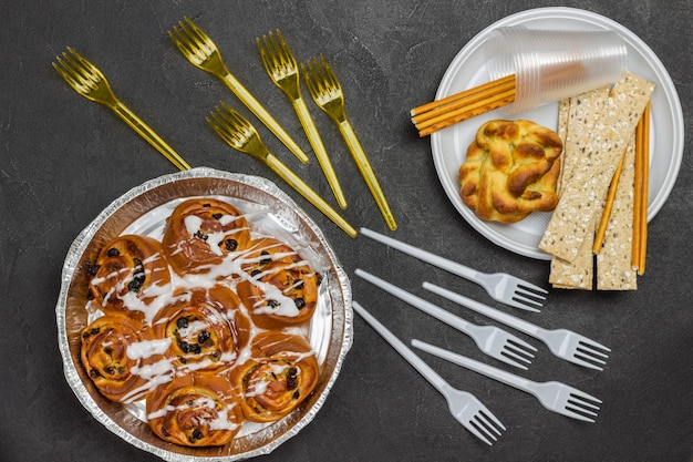 Rosinenbrötchen in Auflaufform. Brötchen und Knäckebrot in Einweg-Plastikteller.