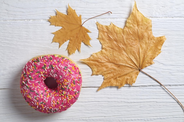 Foto rosquilla rosa y hojas de arce