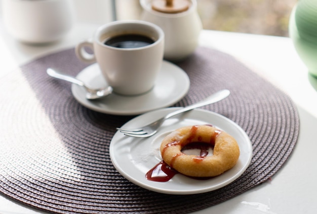 Rosquillas de azúcar en polvo frescas con chocolate y taza de café en la mesa de madera en la cafetería