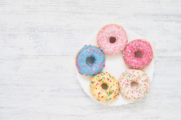 Rosquillas dulces y coloridas en el plato blanco sobre la mesa