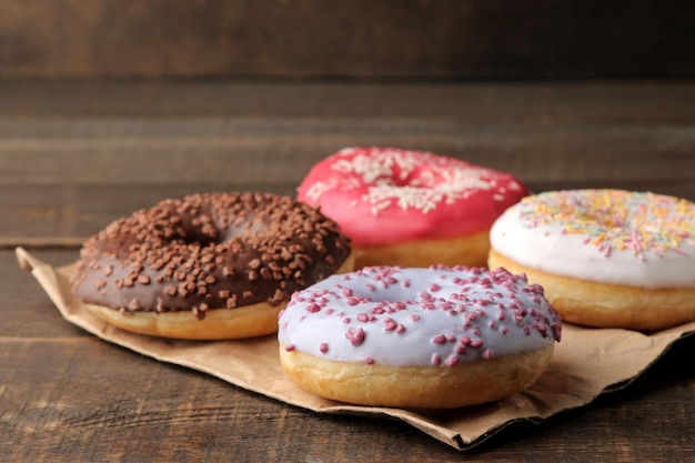 Rosquillas dulces variadas con glaseado y chispas sobre una mesa de madera marrón