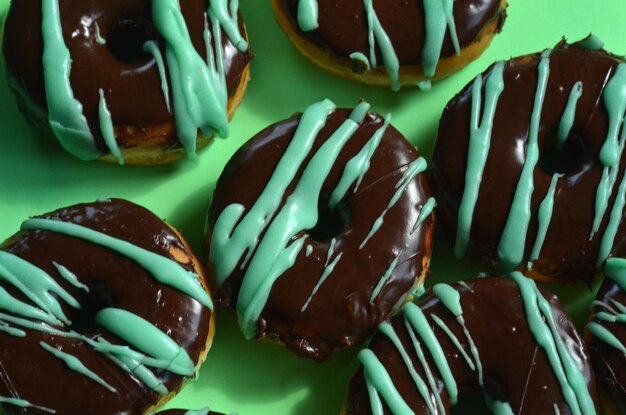 Rosquillas con glaseado de chocolate y rayas de glaseado verde en papel verde