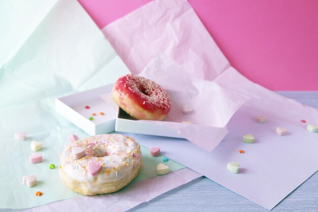 Rosquillas recién horneadas glaseadas con varios tonos rosas y espolvoreadas con corazones de caramelo