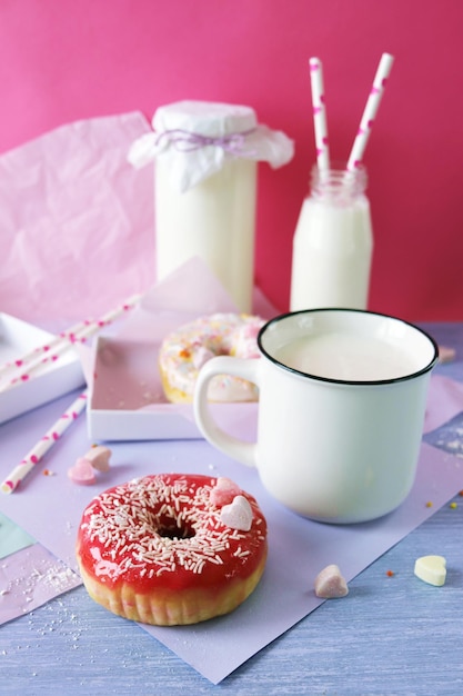 Rosquillas recién horneadas glaseadas con varios tonos rosas y espolvoreadas con corazones de caramelo