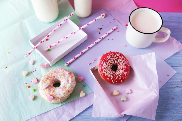 Rosquillas recién horneadas glaseadas con varios tonos rosas y espolvoreadas con leche de corazones de caramelo