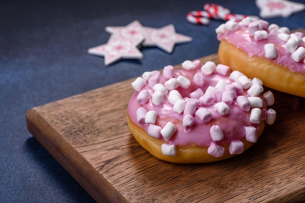 Rosquinha de vidro rosa e marshmallow com decorações de Natal em uma tábua de madeira