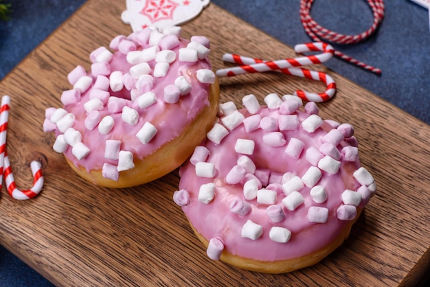 Rosquinha de vidro rosa e marshmallow com decorações de Natal em uma tábua de madeira