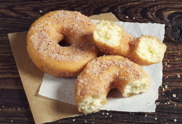 Rosquinha e duas metades em papel, colocadas em uma mesa de madeira