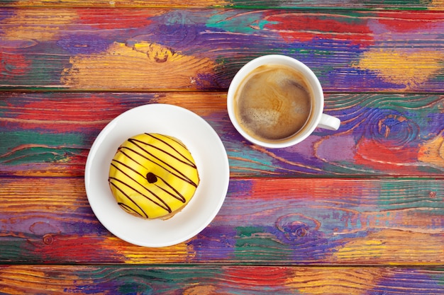 Rosquinha fresca com café na superfície de madeira, vista superior