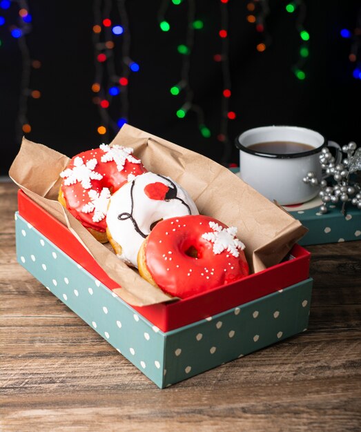 rosquinhas brancas e vermelhas decoradas para o natal em uma caixa verde com luzes de fundo