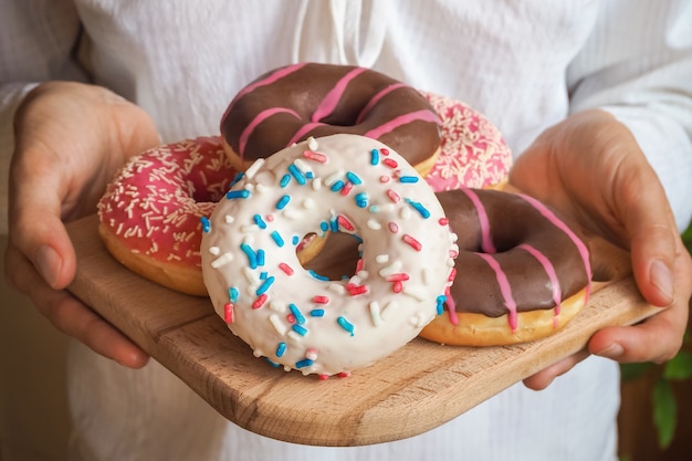 Rosquinhas coloridas em um prato são servidas em suas mãos.