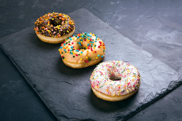 Rosquinhas de Berlim com esmalte em um fundo preto.