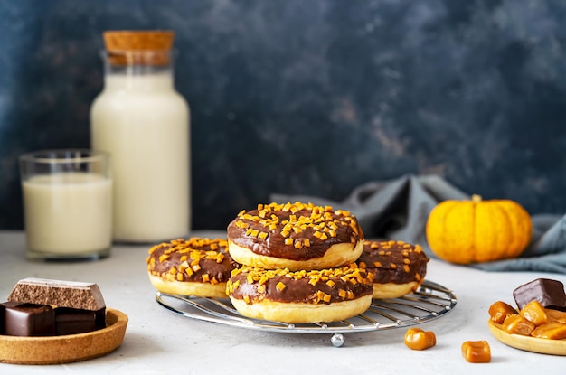 Rosquinhas de chocolate com caramelo Grupo de rosquinhas em suporte de ferro fundo cinza escuro ingredientes de leite