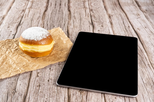 Rosquinhas de creme brasileiras em um papel pardo ao lado de um tablet