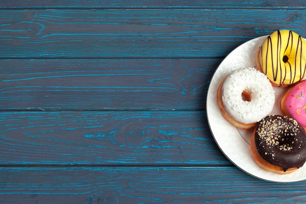 Rosquinhas frescas coloridas sobre fundo azul de superfície de madeira azul escuro