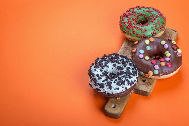 Rosquinhas variadas com glacê e sensações em um fundo laranja