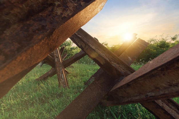 Rostige panzerabwehr-igel auf dem nassen gras auf sonnenuntergangshintergrundkrieg in der ukraine