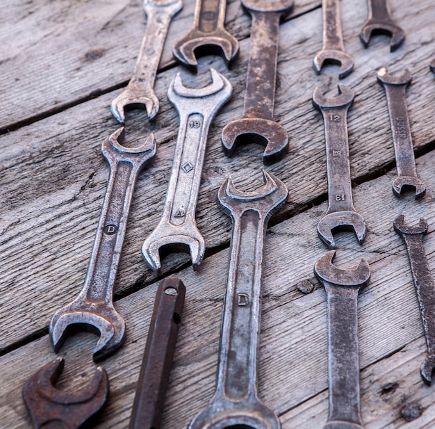 Rostige Werkzeuge des Metallschlüssels, die auf einem schwarzen Holztisch liegen. Hammer, Meißel, Bügelsäge, Metallschlüssel