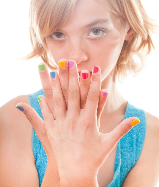 Foto rosto de adolescente loira com unhas multicoloridas close-up