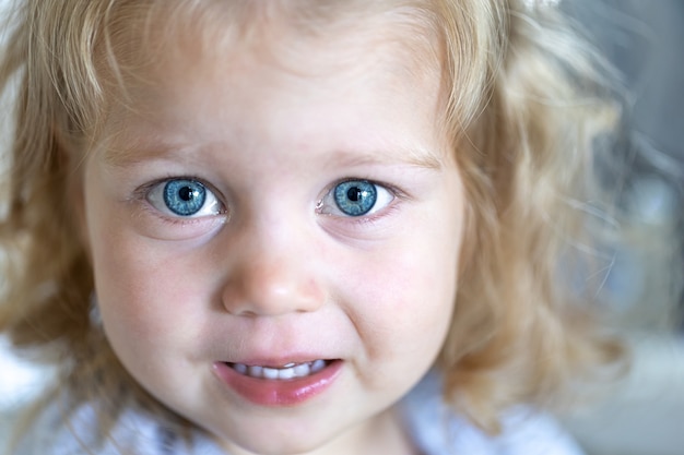 Rosto de close-up de uma menina bonita com grandes olhos azuis cheios de tristeza.