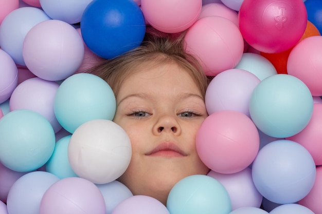 Rosto de criança entre bolas multicoloridas no playground dentro