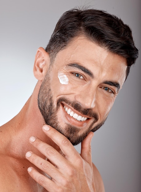 Rosto de homem e creme para cuidados com a pele e closeup de beleza com retrato facial de protetor solar e hidratante Loção de bem-estar da pele e brilho com maquete de cuidados cosméticos de modelo feliz contra o fundo do estúdio