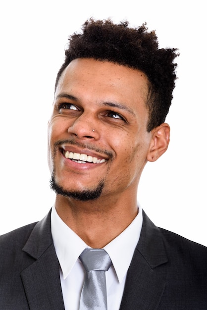 Rosto de jovem empresário africano feliz sorrindo enquanto pensa isolado no branco