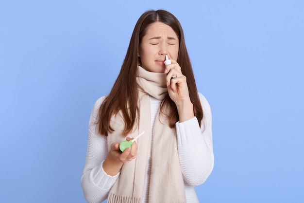 Rosto de mulher caucasiana carrancudo enquanto usa spray nasal