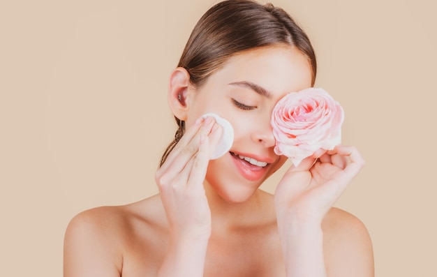 Rosto de mulher de beleza com flores rosas de maquiagem natural e com almofadas de algodão esponja bola de algodão Cosméticos de bem-estar femininos Conceito de cuidados com a pele de spa e bem-estar Tratamento facial