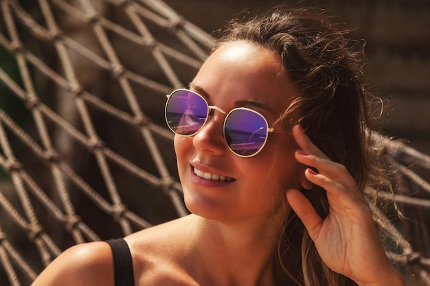 Foto rosto de mulher em óculos de sol relaxantes na praia tropical na rede